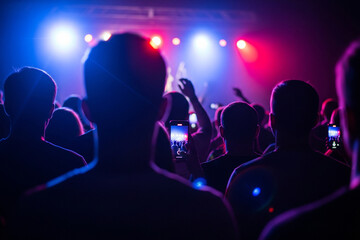 Naklejka premium Concert Crowd Silhouettes with Phone Recording, Stage Lights, and Excitement