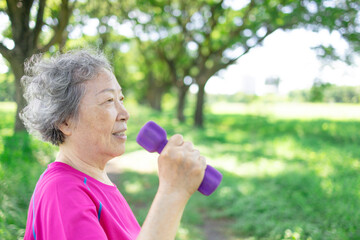 Happy Asian senior woman lifting dumbbell