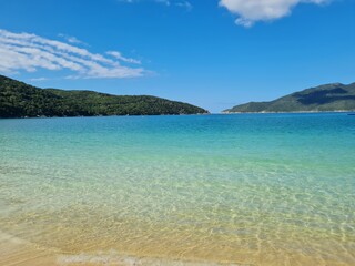 Praia do Forno, Arraial do Cabo, Rio de Janeiro – Brazil: Soft white sand, crystal-clear water, lush vegetation, a tropical Brazilian landscape, and a paradisiacal scene in Brazil’s Lakes Region.