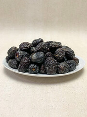 close up photo of a pile of Ajwa dates on a plate. ready to be served.