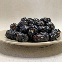 close up photo of a pile of Ajwa dates on a plate. ready to be served.