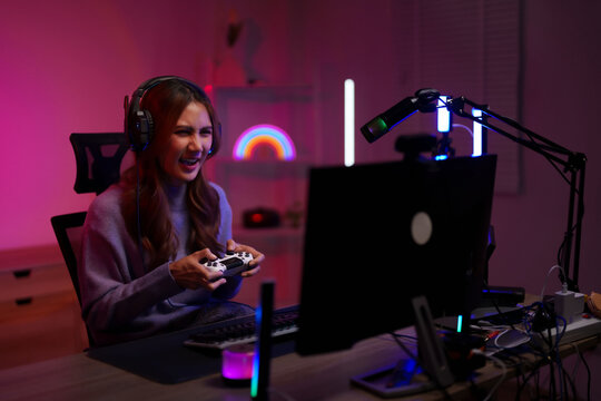 Asian female streamer gaming online intense video game play home studio setup