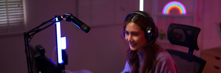 Asian young adult woman stream game broadcast live online home room gaming setup desk computer microphone rgb lighting neon sign technology