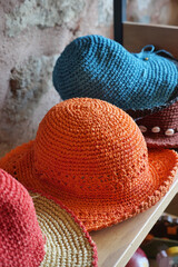 Colorful handmade hats displayed on wooden shelf