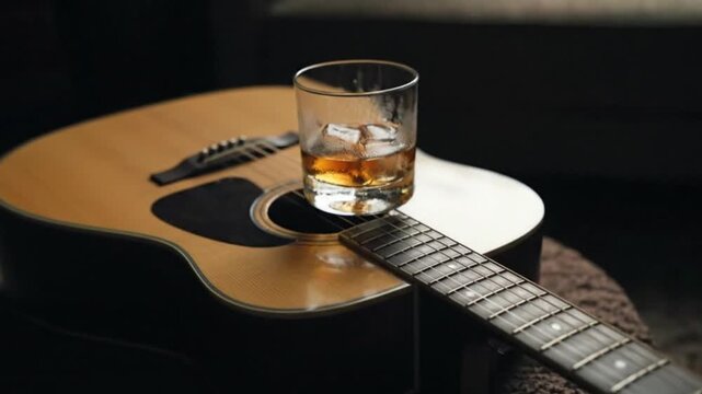 A glass of liquor atop an acoustic guitar