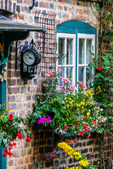 Flowers and a clock outside an English country cottage