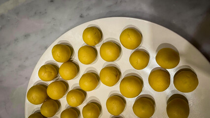 Dough Balls Ready: An overhead shot of perfectly shaped yellow dough balls, neatly arranged on a...