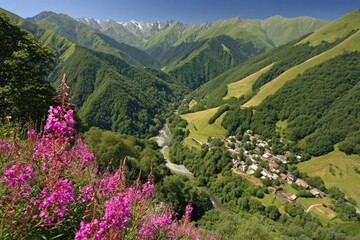 Mountain valley with pink wildflowers, a village, and a river. Lush green slopes, snow-capped peaks, sunny day