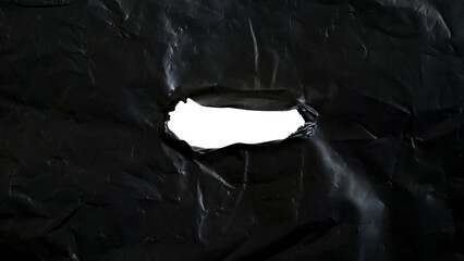 Black plastic with ripped hole in the middle of the surface isolated on transparent background