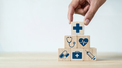 Hand stacking wooden blocks with medical symbols representing healthcare services and patient care building a foundation