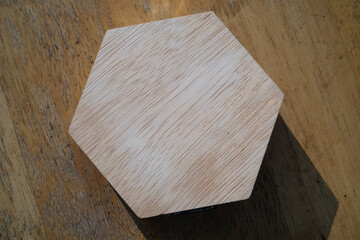 Top angle shot Hexagonal wooden jewelry box and shadow. Close-up of isolated hexagonal wooden box. Single objects. Texture and silhouette of jewelry box. Negative space.