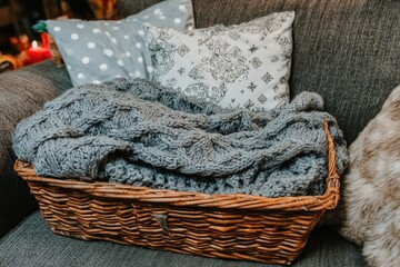 Cozy wicker basket with gray knit blanket and pillows