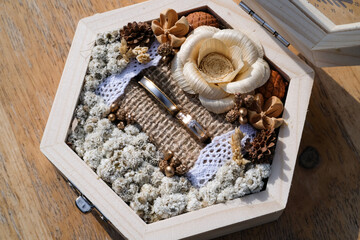 Tabletop shot of an aesthetic hexagonal ring box. Dried flowers and burlap adorn a jewelry box with...