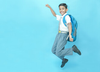 Excited Indian schoolboy student jumping with joy isolated over blue background, Education knowledge concept. Admission open.
