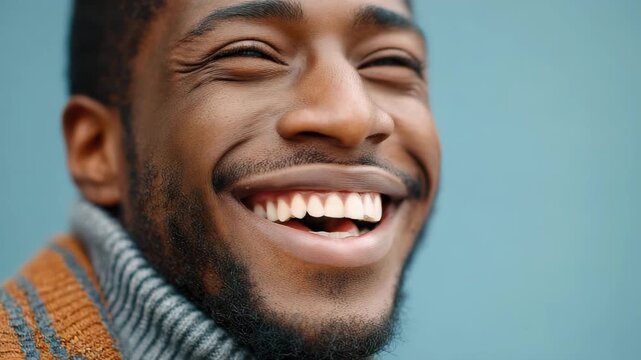 Smiling man with beard showing levity and laughter joyful close up portrait wearing warm sweater with striped pattern against