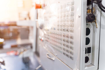 Closeup and crop control buttons center of automated CNC vertical machine with sun bright and...