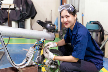 An Asian female electrical engineer checks the wiring system to repair an electric bicycle in workshop