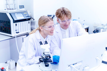 Two scientists, medical technique working together and looking data at monitor in the laboratory. Collaboration and technology for research, discussion and digital analysis