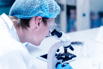 Closeup scientist looking in microscope while working on medical research in science laboratory