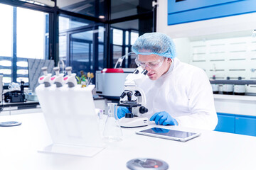 Scientist looking in microscope while working on medical research in science laboratory