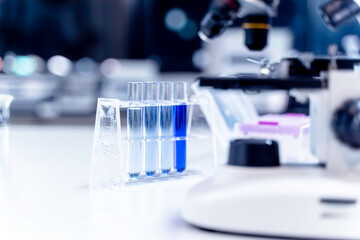 Closeup blue chemical in laboratory test tubes with a microscope on table in laboratory and blurred...