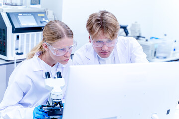 Two scientists, medical technique working together and looking data at monitor in the laboratory. Collaboration and technology for research, discussion and digital analysis