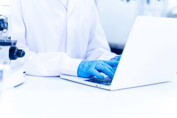Closeup and crop hands of scientist working data on laptop in the laboratory.