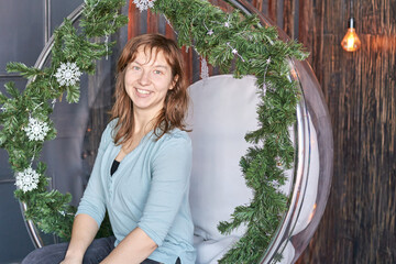Smiling caucasian female adult in holiday decorated chair.