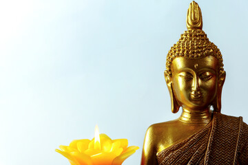 close up of Golden buddha statue with a lit candle evokes peace and tranquility, ideal for...
