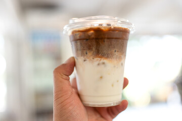 Close up of a glass of iced latte coffee with two layers of fresh milk and espresso shot.
