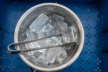 A shiny metal bucket filled with clear ice cubes. Top view