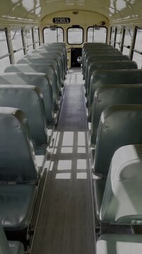 Empty school bus interior, long perspective, dark green seats, and overhead lighting create a quiet, nostalgic mood