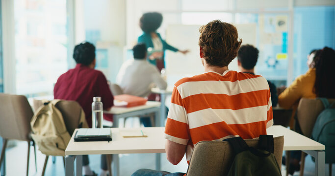 Listening, professor and lecture with students in classroom for college, learning and lesson. University, education and teaching with back of person on campus for assignment, study and curriculum
