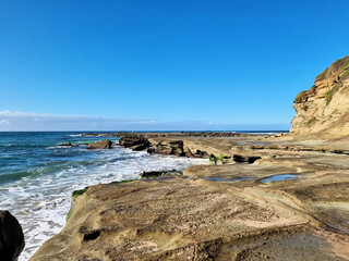Ocean waves crashing over an eroded rock platform and boulders at Soldiers Point New South Wales Australia. 