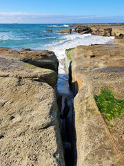 Ocean waves crashing over an eroded rock platform and boulders at Soldiers Point New South Wales Australia. 