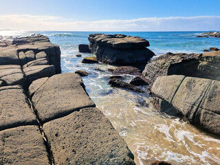 Ocean waves crashing over an eroded rock platform and boulders at Soldiers Point New South Wales Australia. 