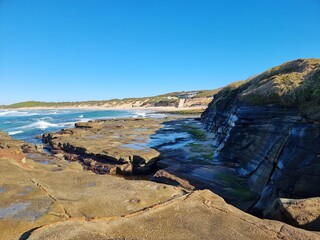 Eroded wave cut rock platform with exposed joint lines. Cliff in the background with a blue sky. Soldiers Point New South Wales Australia
