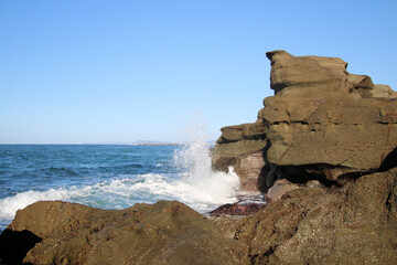 Ocean waves crashing over an eroded rock platform and boulders at Soldiers Point New South Wales Australia. 