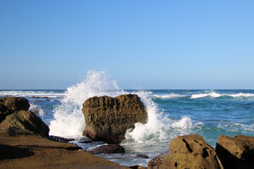 Ocean waves crashing over an eroded rock platform and boulders at Soldiers Point New South Wales Australia. 