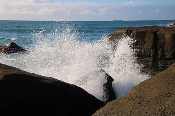 Ocean waves crashing over an eroded rock platform and boulders at Soldiers Point New South Wales Australia. 