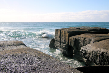 Ocean waves crashing over an eroded rock platform and boulders at Soldiers Point New South Wales Australia. 
