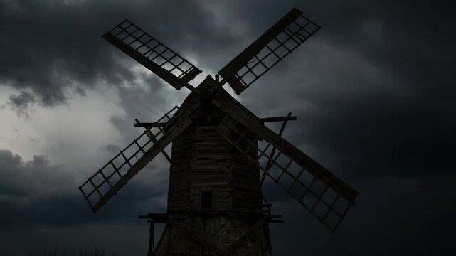 Old windmill silhouette against dark stormy sky