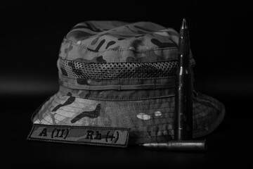 Stark monochrome image of a soldier's kit: camouflage hat, blood patch, and ammunition,...