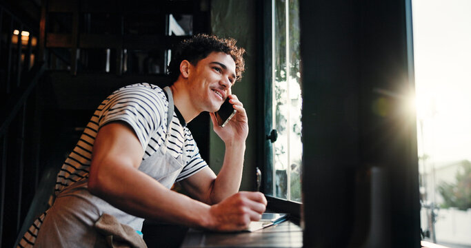 Waiter, man and phone call at coffee shop with notes, contact supplier for deal, negotiation or order by window. Person, manager and listen with smartphone, smile and talk for stock discount at cafe - Powered by Adobe
