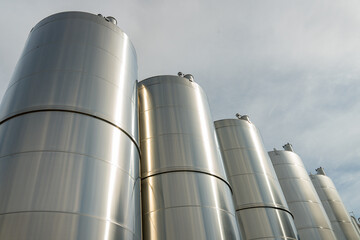 Gros plan de grandes cuves en inox photographiées en extérieur, illustrant leur surface métallique brillante et leur usage industriel.