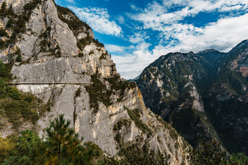 Sunlit mountain walkway overlooking deep gorge in Balagezong, Shangri-La, China