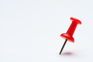 Single red pushpin stuck in a white surface
