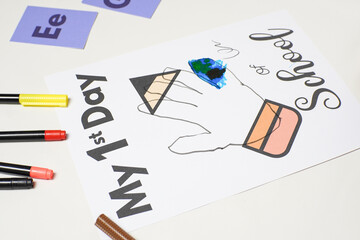 A hand-drawn first day of school worksheet partially colored with blue and green, surrounded by...