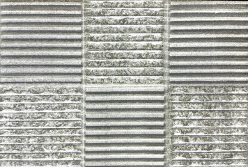 Close up of grey stone with horizontal fluted stripes pattern. Grey carved stone tiles in fluted and checkerboard arrangement. Seamless background texture.