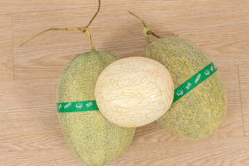 Three green melons with a green ribbon tied around them